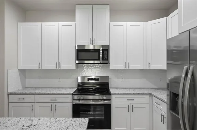 a kitchen with white cabinets and black appliances