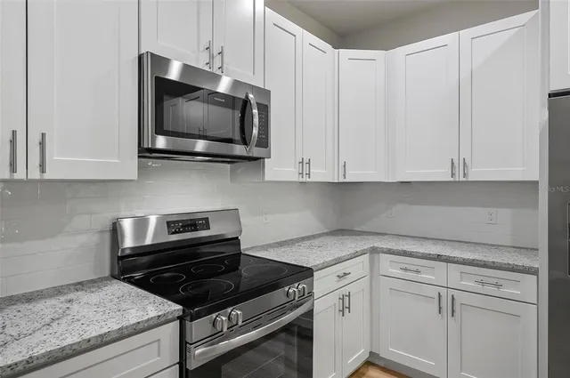 a kitchen with stainless steel appliances granite countertop white cabinets granite counter tops and a wooden floors