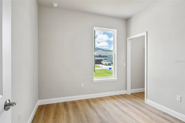 an empty room with wooden floor fan and windows