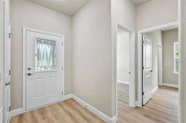 a kitchen with stainless steel appliances granite countertop a stove a refrigerator a sink and white cabinets with wooden floor