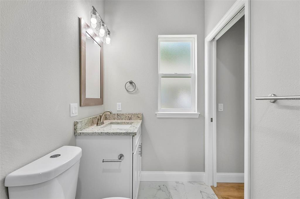 43 Eton Lane, Unit A Palm Coast, FL 32164 - Photo 49 of 78 a bathroom with a granite countertop sink a toilet and a mirror