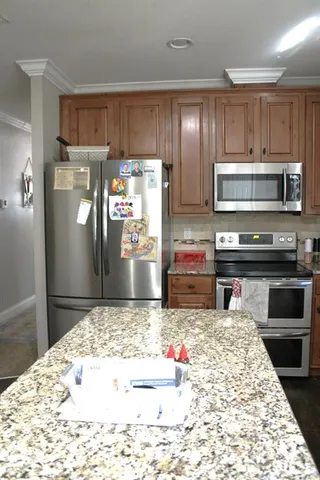 a kitchen with kitchen island granite countertop a refrigerator stove and oven