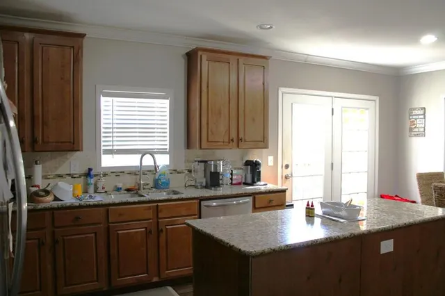 a kitchen with stainless steel appliances granite countertop a sink a window and cabinets