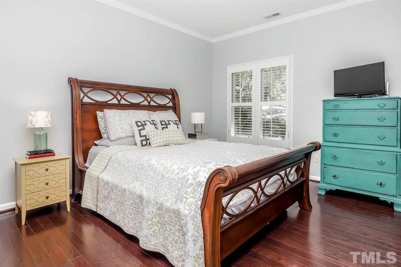 1001 Brighthurst Drive, Unit 103 Raleigh, NC 27605 - Photo 11 of 16 a bedroom with a bed and a flat tv screen on a dresser