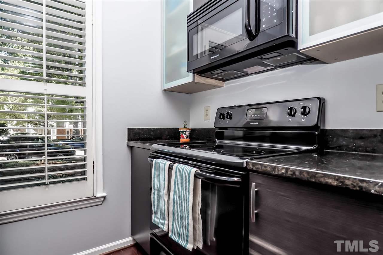 1001 Brighthurst Drive, Unit 103 Raleigh, NC 27605 - Photo 10 of 16 a kitchen with stainless steel appliances granite countertop a stove and a microwave