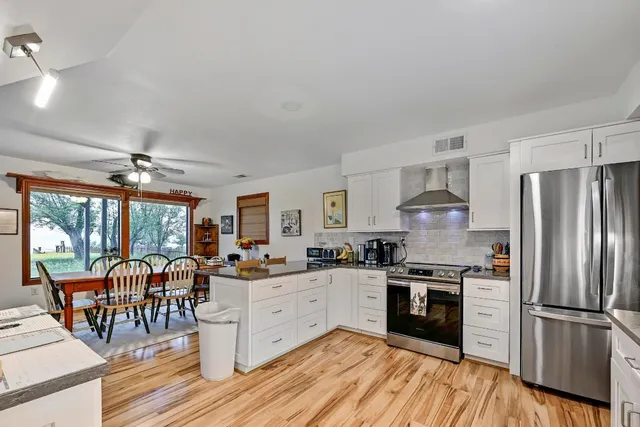 a kitchen with stainless steel appliances granite countertop a stove refrigerator and a view of living room