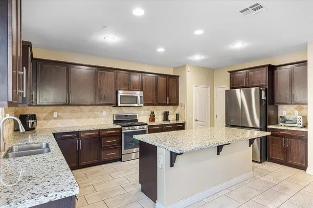 a kitchen with stainless steel appliances granite countertop a sink stove refrigerator and cabinets