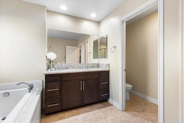 a spacious bathroom with a granite countertop sink a mirror and a bathtub