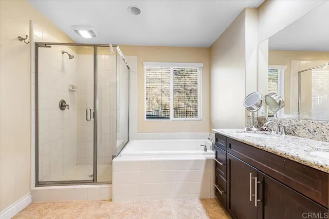 a bathroom with a granite countertop sink a mirror a bathtub and next to a window