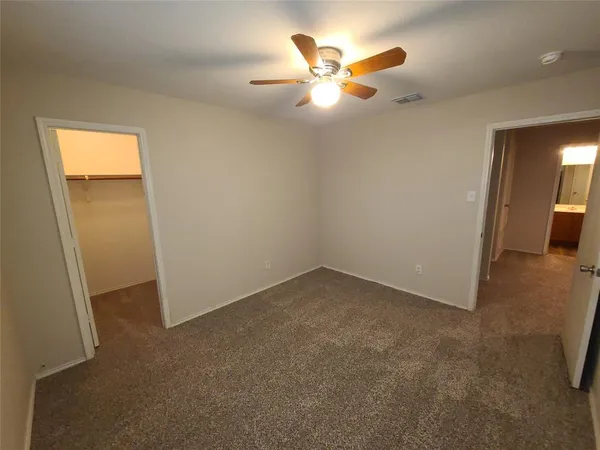 an empty room with closet and a chandelier fan