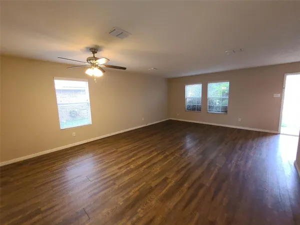a view of an empty room with wooden floor and a window