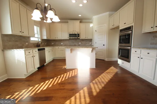 a large kitchen with cabinets wooden floor stainless steel appliances and chandelier
