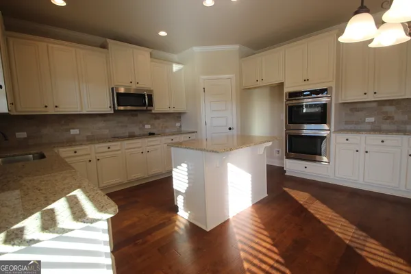 a kitchen with stainless steel appliances granite countertop a stove a sink and a microwave