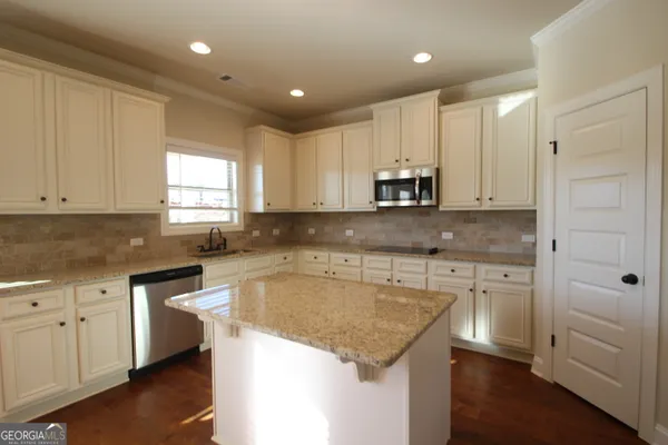 a kitchen with kitchen island white cabinets appliances and a window