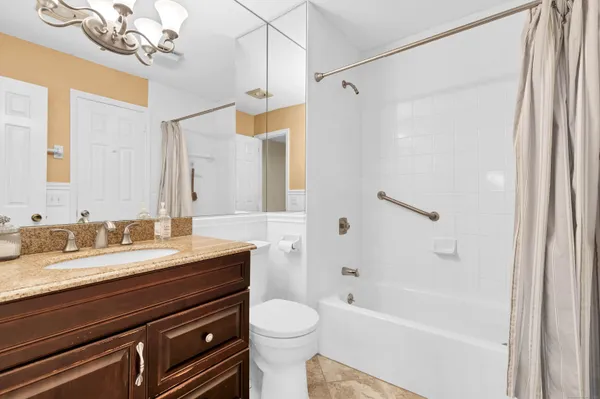 a bathroom with a granite countertop sink a toilet a mirror and shower