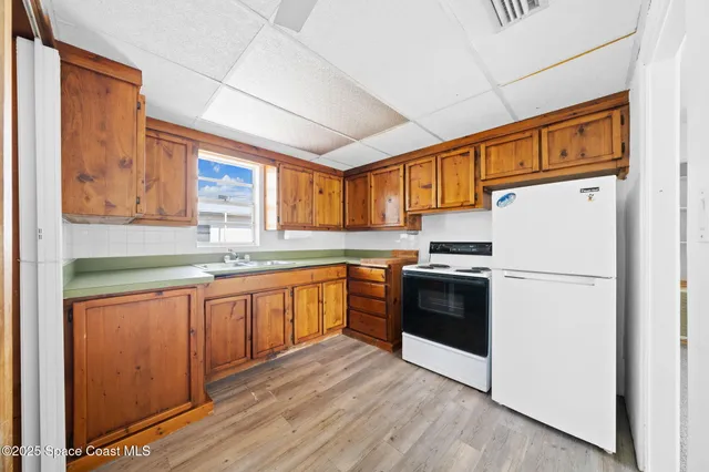 a kitchen with granite countertop a refrigerator stove top oven sink and cabinets