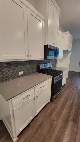 a kitchen with granite countertop white cabinets and black appliances