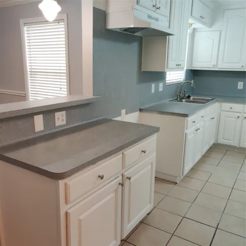 a kitchen with granite countertop a sink window and cabinets