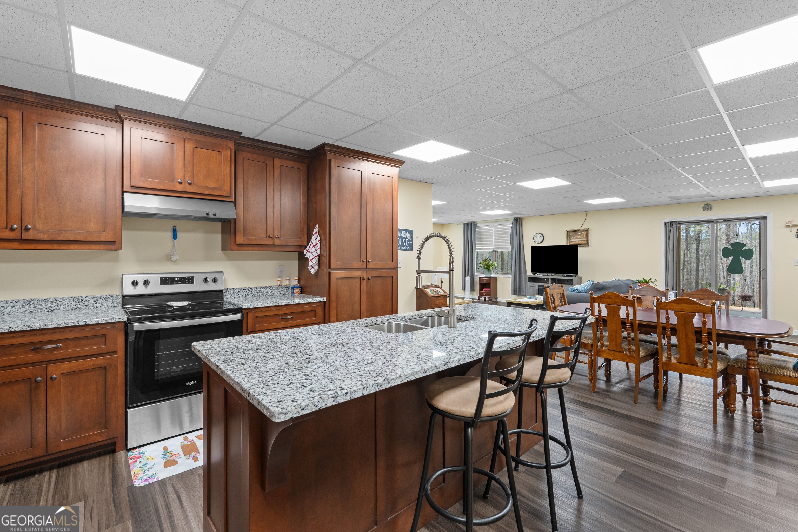 733 Cherry Road Franklin, GA 30217 - Photo 55 of 88 a kitchen with stainless steel appliances granite countertop a stove a refrigerator a kitchen island a dining table and chairs with wooden floor