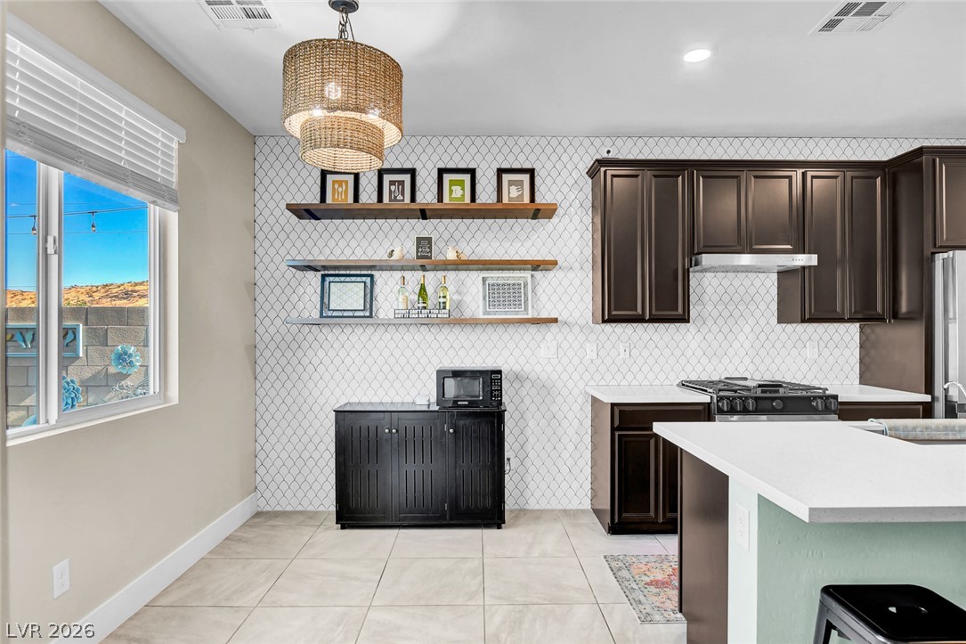 9688 Rankin Rdg Court Las Vegas, NV 89178 - Photo 14 of 53 A well-appointed kitchen features a modern gas range and stylish open shelving against a patterned tile backsplash.