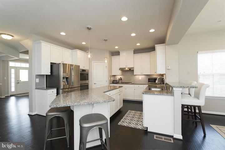 10431 Windlass Run Road Baltimore, MD 21220 - Photo 9 of 30 a kitchen with stainless steel appliances granite countertop a table chairs sink refrigerator and microwave