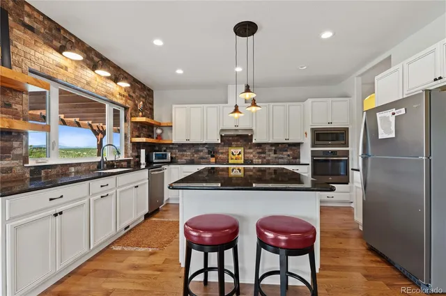 a kitchen with stainless steel appliances granite countertop a sink a stove and a refrigerator