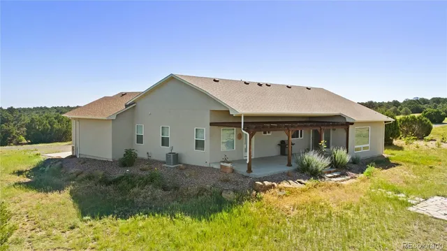 a front view of house with yard and trees in the background