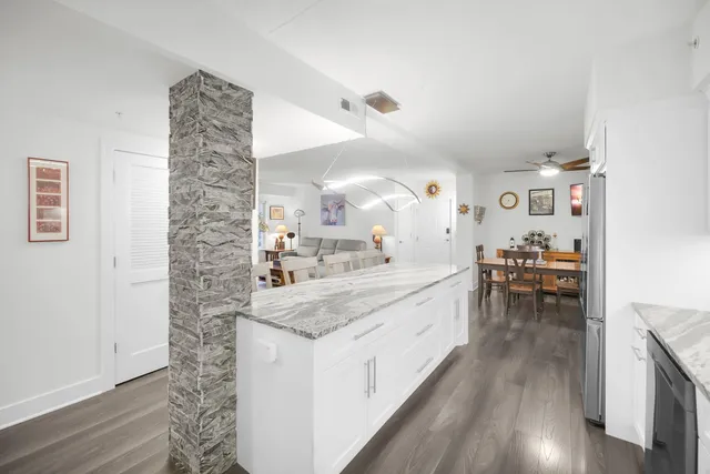 a large white kitchen with a lot of counter space and wooden floor