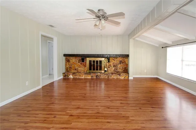 a view of empty room with wooden floor and fan