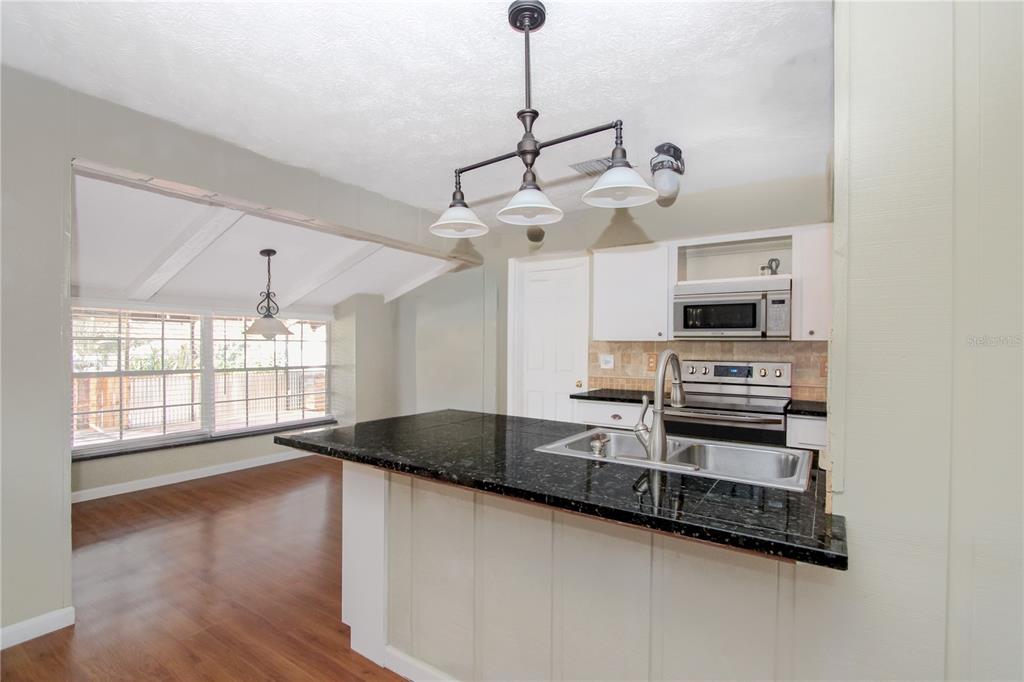 106 Phillips Drive Seffner, FL 33584 - Photo 10 of 48 a kitchen with stainless steel appliances a stove a sink and white cabinets with wooden floor