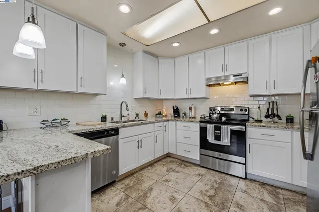a kitchen with granite countertop sink stove and cabinets