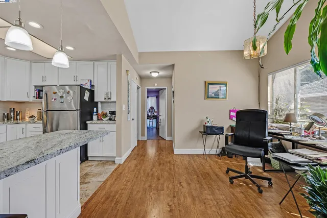 a living room with stainless steel appliances granite countertop furniture wooden floor and a kitchen view