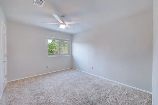 an empty room with a window and ceiling fan