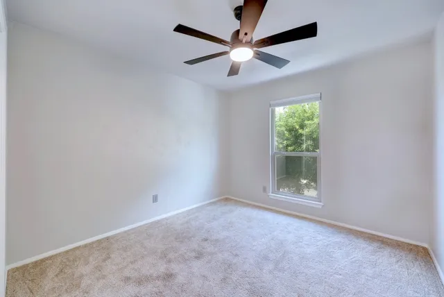 an empty room with a ceiling fan and window