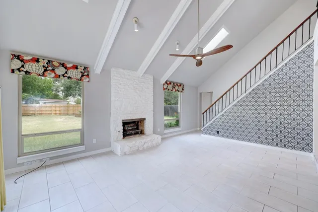 a view of a livingroom with wooden floor a ceiling fan and windows