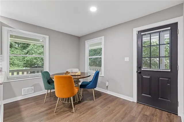 a kitchen with stainless steel appliances granite countertop a dining table chairs and a refrigerator