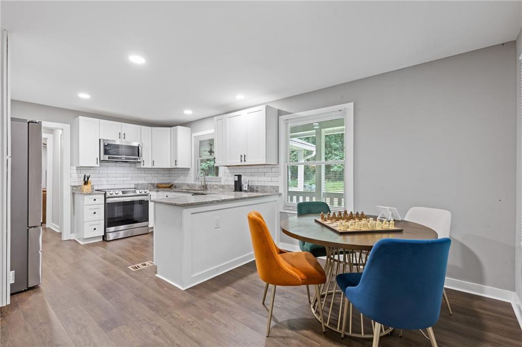 742 Mountain View Drive Stone Mountain, GA 30083 - Photo 20 of 43 a kitchen with stainless steel appliances granite countertop a dining table chairs and a refrigerator