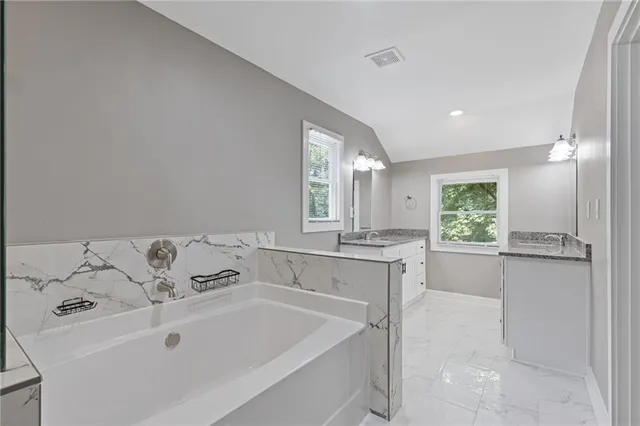 a bathroom with a toilet a sink a mirror a window and vanity