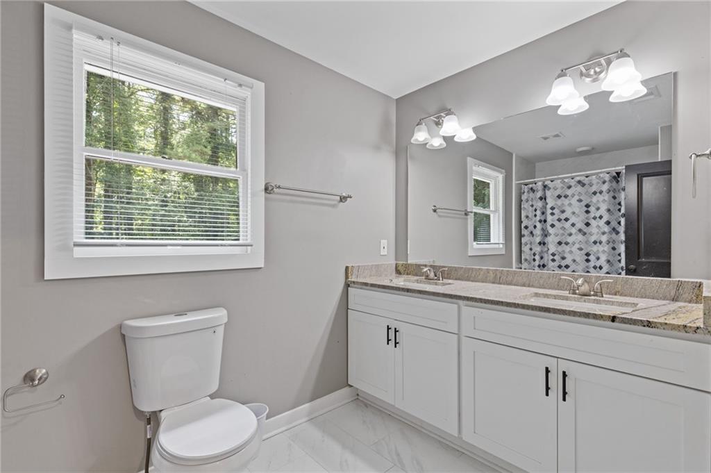 742 Mountain View Drive Stone Mountain, GA 30083 - Photo 29 of 43 a bathroom with a toilet a sink a mirror a window and vanity