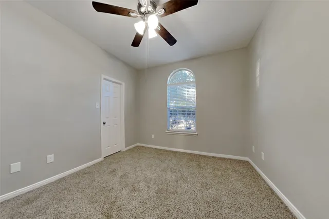 an empty room with a window and a fan