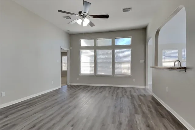 a view of an empty room with a window and wooden floor