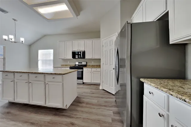 a kitchen with granite countertop white cabinets and stainless steel appliances