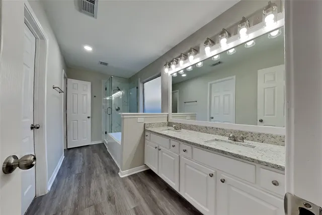 a spacious bathroom with a granite countertop sink toilet a large mirror a and shower