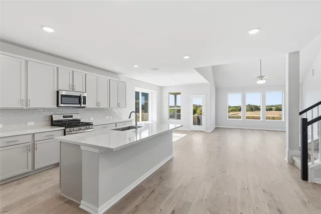 a large kitchen with stainless steel appliances granite countertop a lot of counter space and a wooden floors