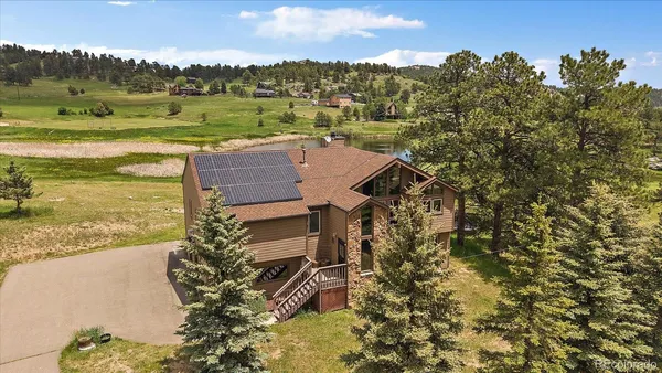 an aerial view of a house with a yard lake and outdoor seating