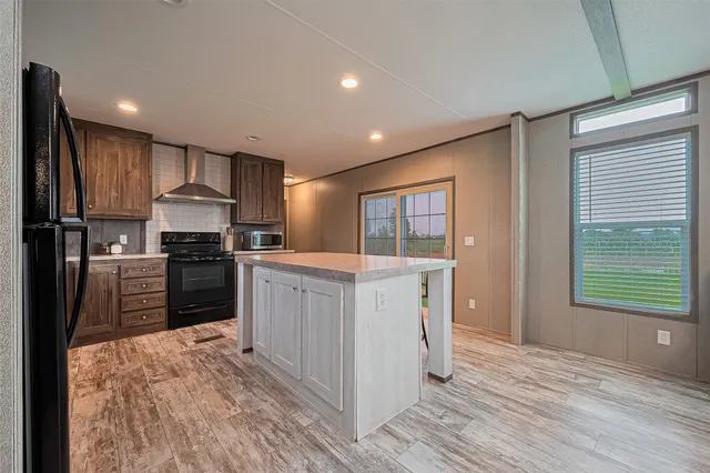 a kitchen with kitchen island granite countertop a refrigerator oven a sink dishwasher and wooden cabinets with wooden floor