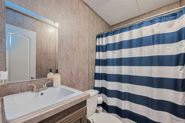 a bathroom with a sink a toilet a mirror and shower