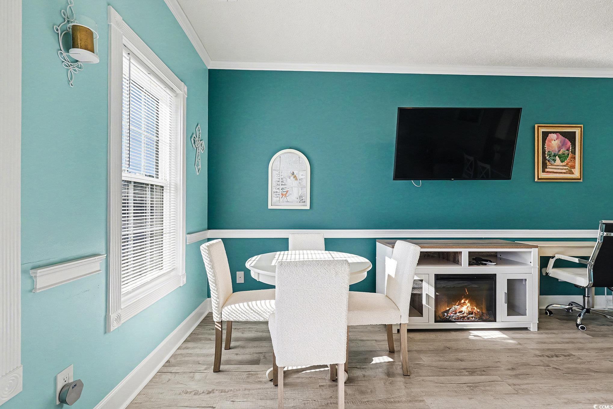 1512 Lanterns Rest Road, Unit 102 Myrtle Beach, SC 29579 - Photo 7 of 21 Dining space with wood finished floors, a glass covered fireplace, ornamental molding, and a desk