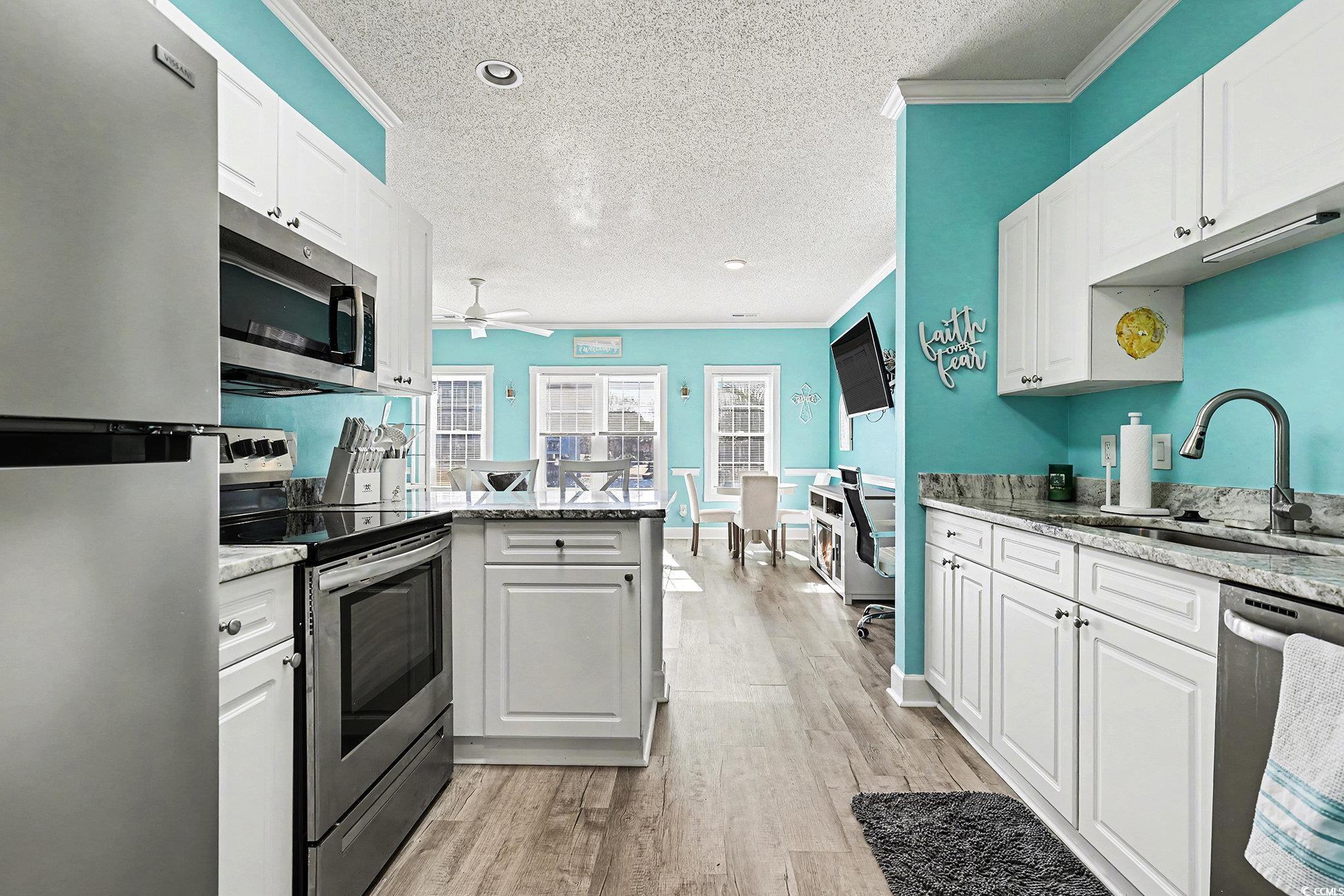 1512 Lanterns Rest Road, Unit 102 Myrtle Beach, SC 29579 - Photo 9 of 21 Kitchen featuring appliances with stainless steel finishes, white cabinetry, a peninsula, a textured ceiling, and light stone countertops