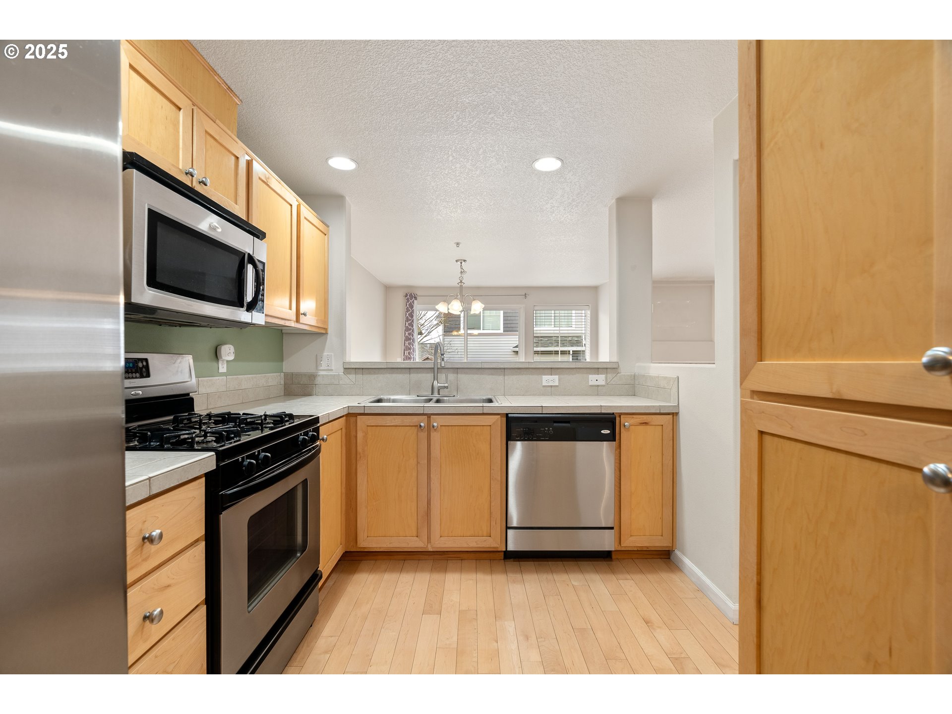 10723 Southwest Canterbury Lane, Unit 102 Portland, OR 97224 - Photo 11 of 30 a kitchen with stainless steel appliances granite countertop a stove a sink and a microwave